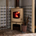 Cream-colored cast iron wood-burning stove with glass-fronted door showing fire studio souk blue star ceramic