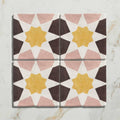 Four square ceramic tiles from Studio Souk featuring yellow star geometric patterns with pink and dark brown shapes on white