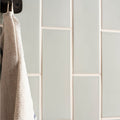 Beige woven towel hanging from a black hook against light gray brick tile sudbury subway tile wall