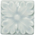 A square glossy white ceramic tile with a raised floral design from the Sudbury Knightsbridge collection