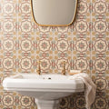 White ceramic pedestal sink with gold-toned faucets on symmetrical floral pattern single tile in county white