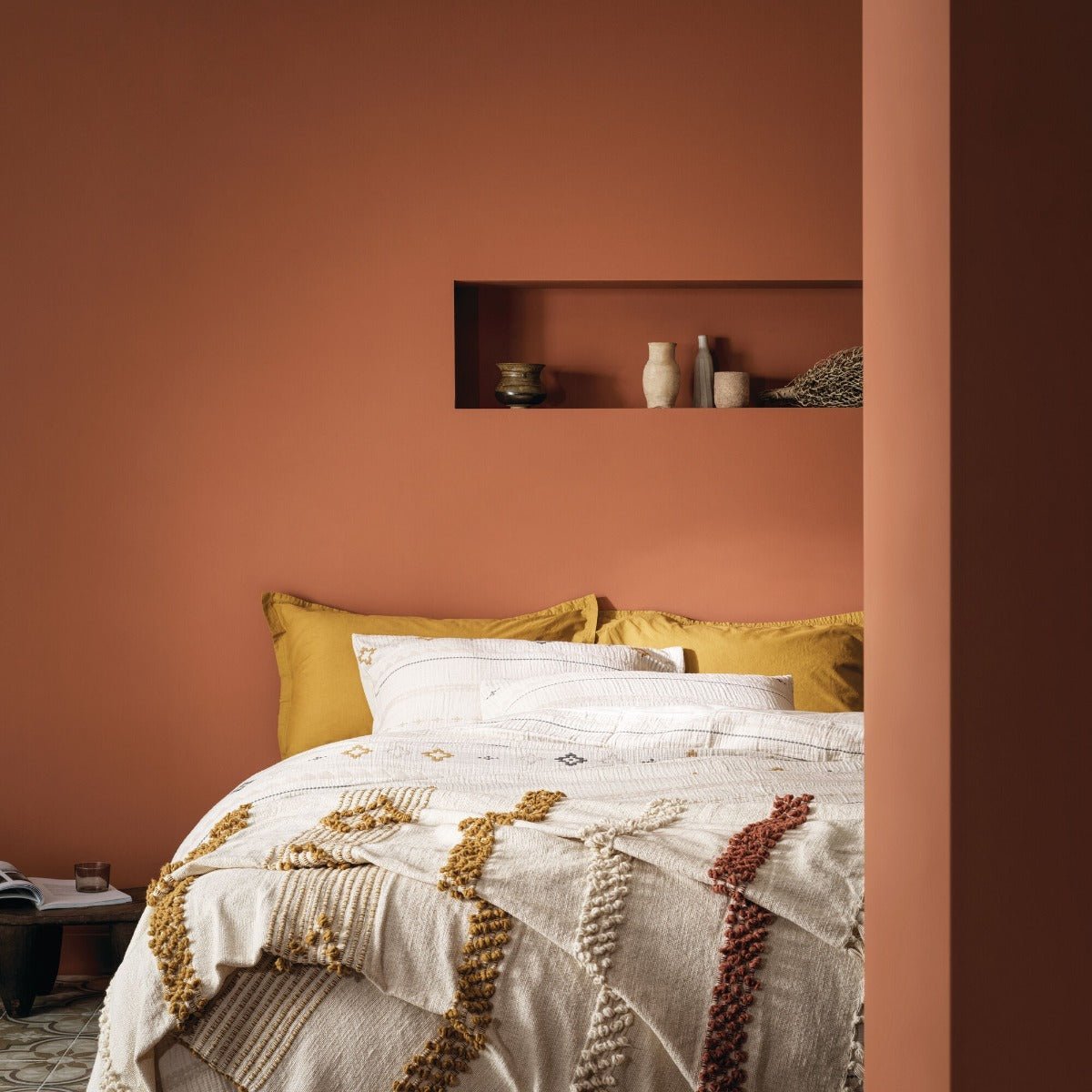 A cozy taos house bed dressed in a textured cream quilt with intricate gold and rust woven trim