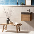 Rustic wooden bench with rough-hewn legs and weathered surface holding textured gray vase and aged stone bowl in field tile teal