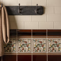 Teapot brown victoria moulding dark wooden coat rack with three ornate hooks mounted above decorative fruit tile border