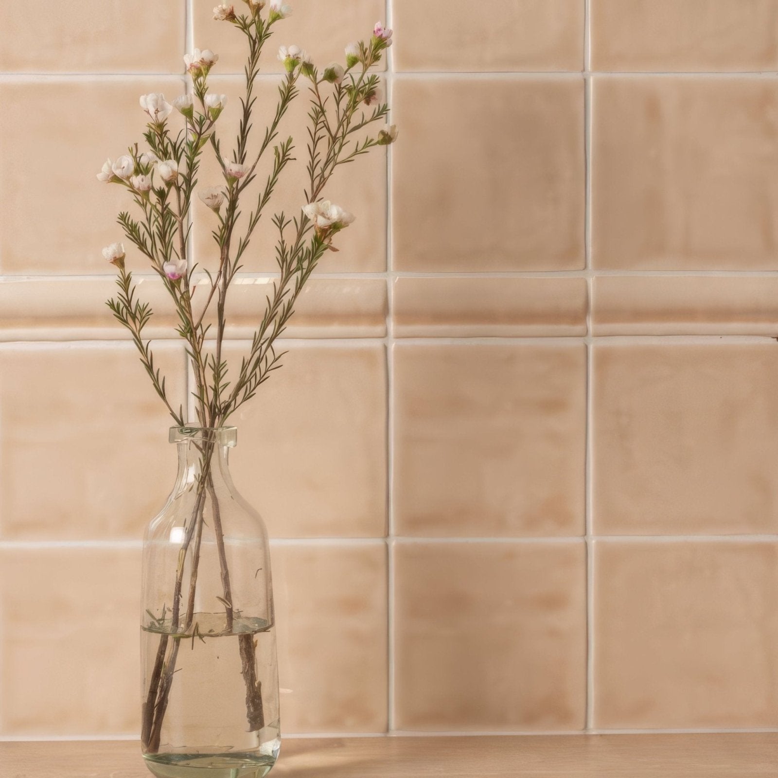 Clear glass bottle holding delicate white and pink flowers showcased with thebes field tile background