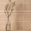 Clear glass bottle holding delicate white and pink flowers showcased with thebes field tile background