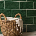 Woven wicker basket with twisted handles and cream towel, styled next to tourmaline brick tile wall