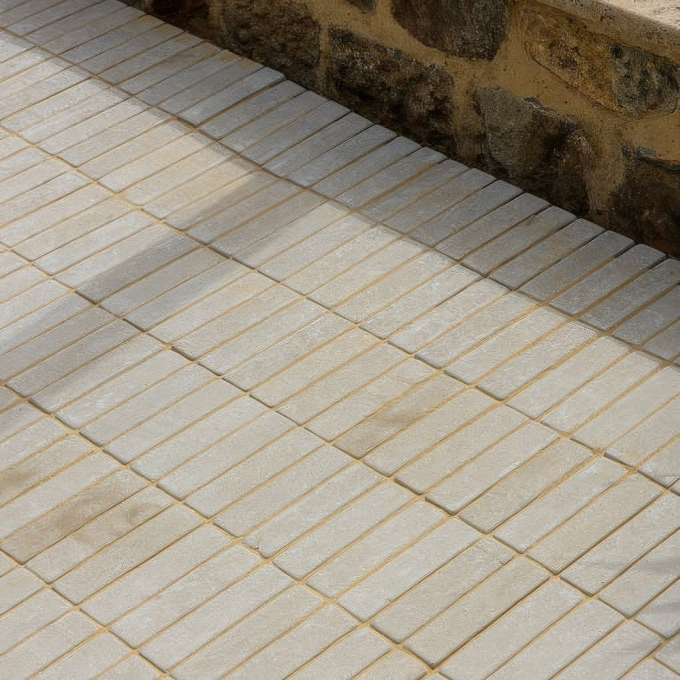 Beige rectangular sandstone pavers arranged in a staggered pattern with visible grout lines from trafalgar sandstone tumbled klinkers