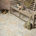 Weathered wooden bench with rustic slats and woven straw broom against trusloe limestone seasoned finish parquet floor