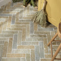 Herringbone-patterned trusloe limestone parquet floor tiles in earthy beige gray and muted brown tones with seasoned finish