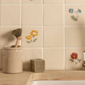 Cream-colored ceramic tile from tubelined floral collection buttercup with hand-painted yellow blue and red floral motifs