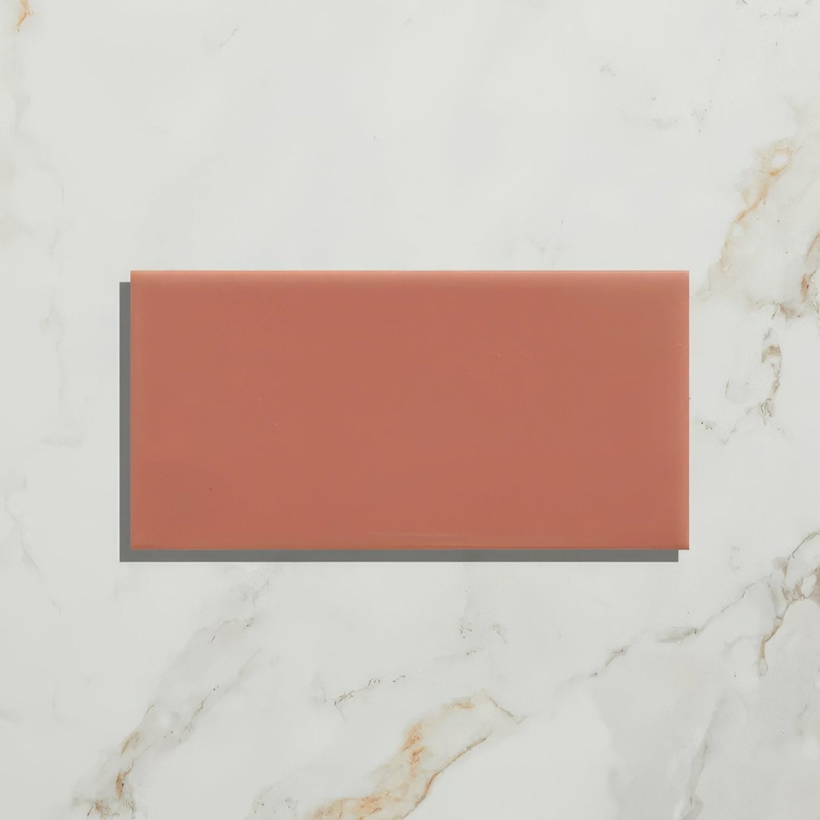 A rectangular terracotta-colored ceramic tile with a smooth matte finish from tunstall ceramic brick coral collection