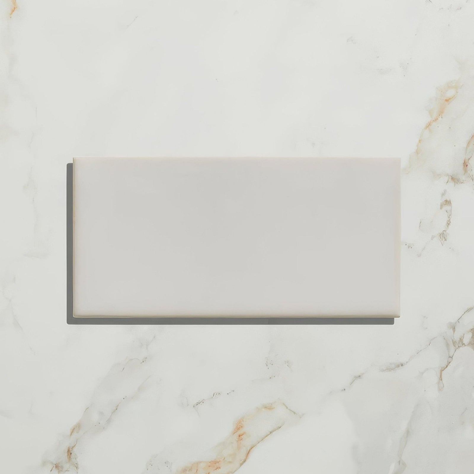 A sleek rectangular white ceramic Tunstall ceramic brick with a smooth matte finish on a marble surface