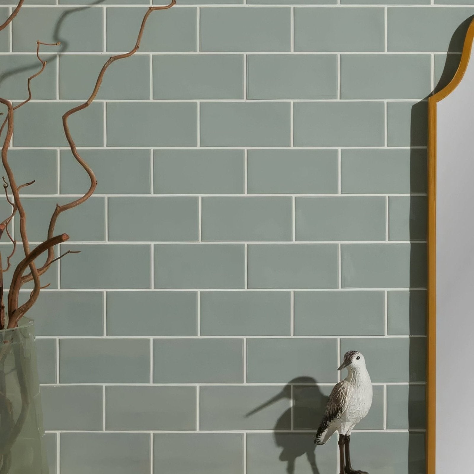 Tunstall ceramic brick fern features a small white and gray bird figurine with black legs against green tiles