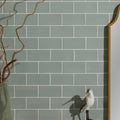 Tunstall ceramic brick fern features a small white and gray bird figurine with black legs against green tiles