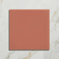 A square terracotta-colored ceramic tile with a smooth matte finish from the tunstall ceramic coral square collection