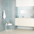 The bathroom features light blue glossy tiles with a subtle textured finish in Ultimo Shell Iridescent Mosaic