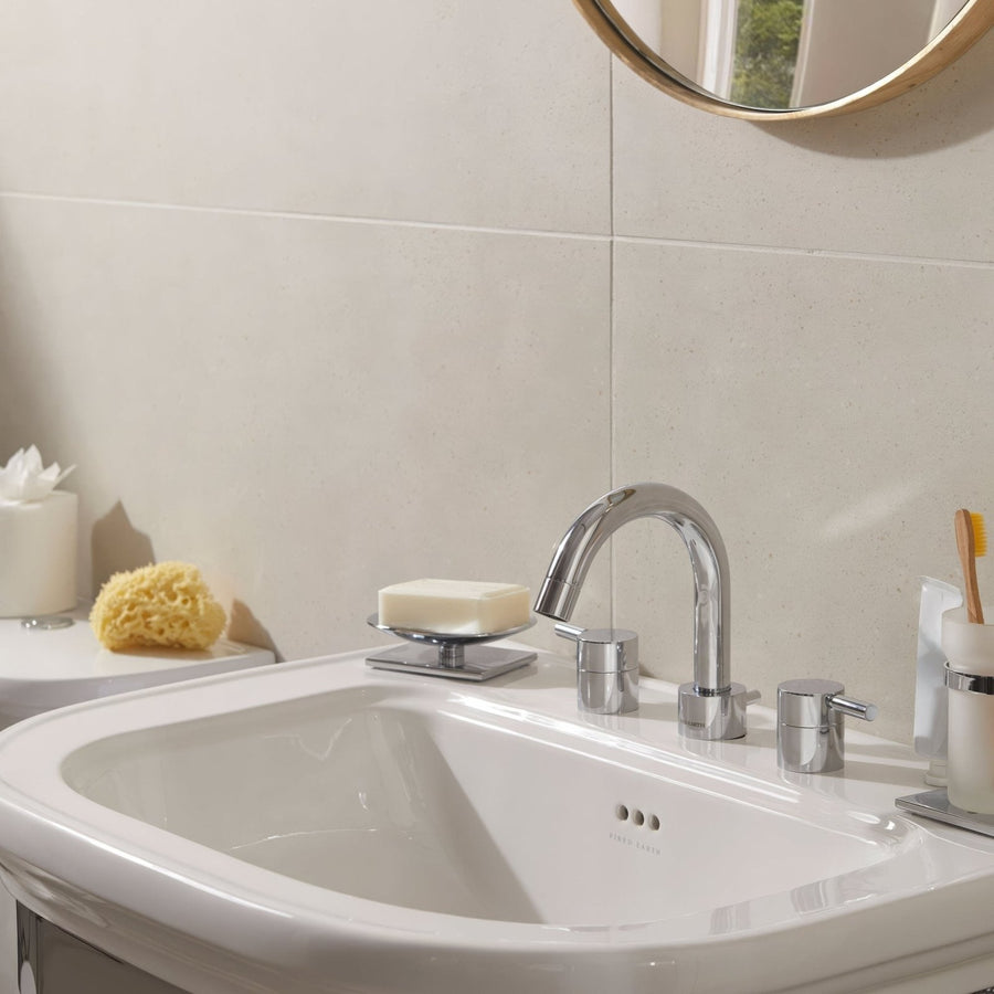 Chrome-finished faucet with sleek curved spout and two handles for hot and cold water in umbrian white 60 x 60cm