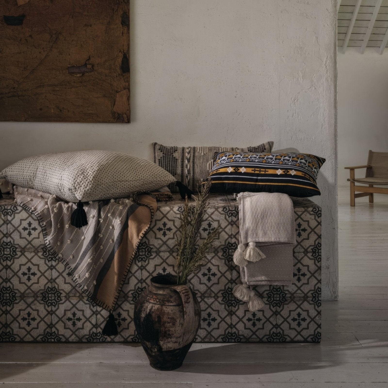 A rustic earth toned ceramic vase with a weathered finish and two handles on urban callizo patterned porcelain tile