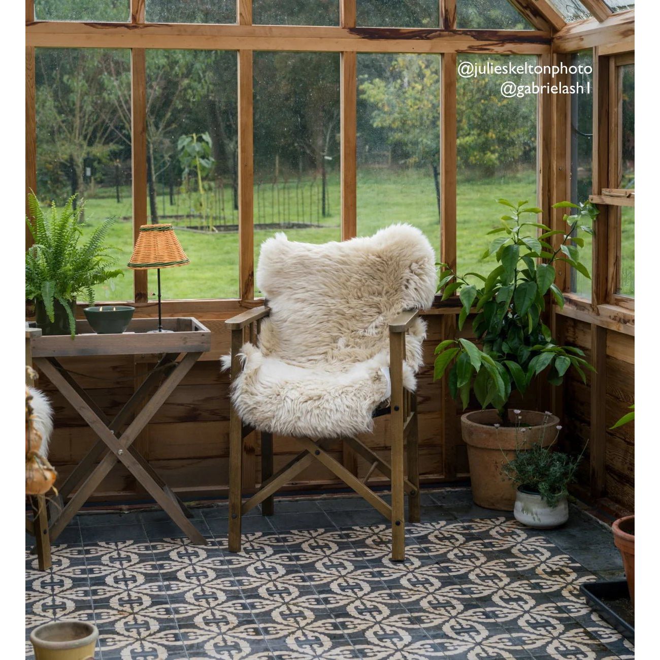 A cozy wooden chair draped with a fluffy off-white sheepskin throw on urban velasco patterned porcelain tile floor