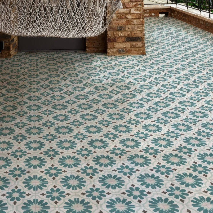 Teal and white patterned mosaic floor tiles with a repeating floral design in vacation porcelain cordoba style