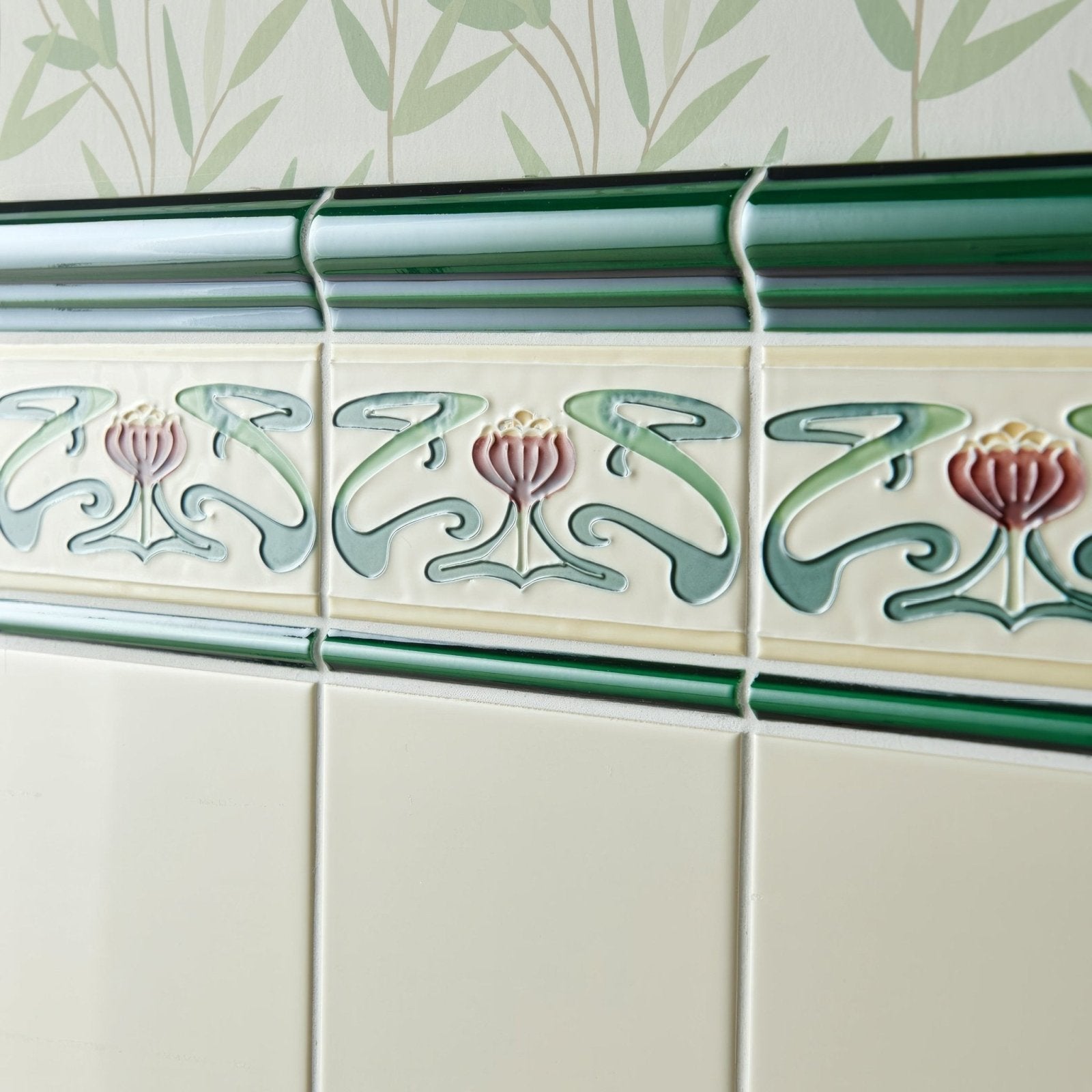 Victorian green Albert moulding featuring art deco ceramic tile border with raised pink and sage floral motifs on cream