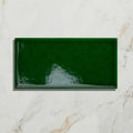 A glossy emerald green rectangular Victorian Style™ wall ceramic tile with subtle wavy texture and crackle glaze