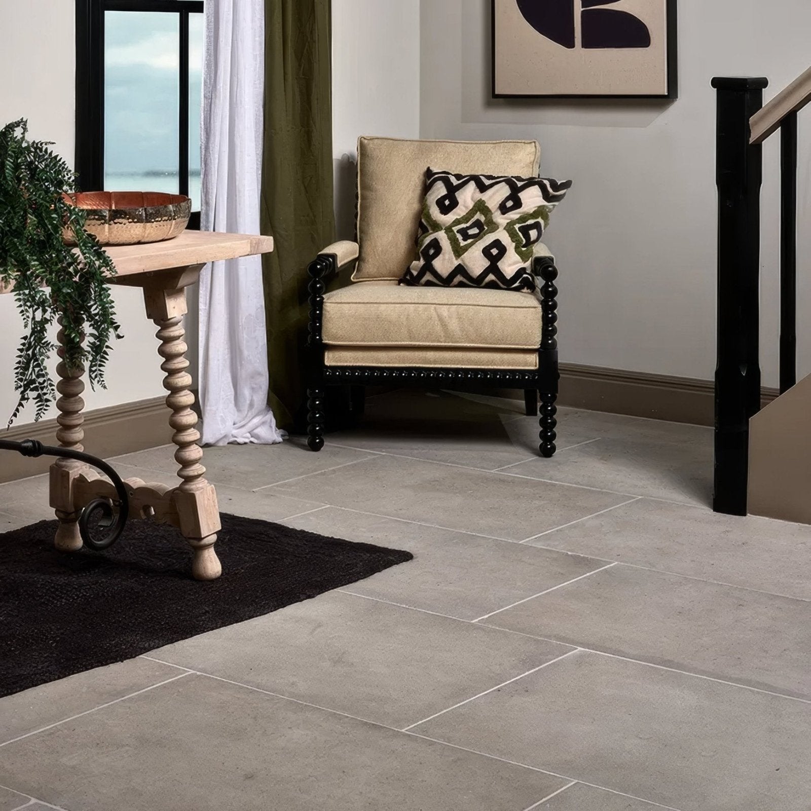 Beige upholstered vienne limestone satino armchair with black spindle legs and patterned throw pillow