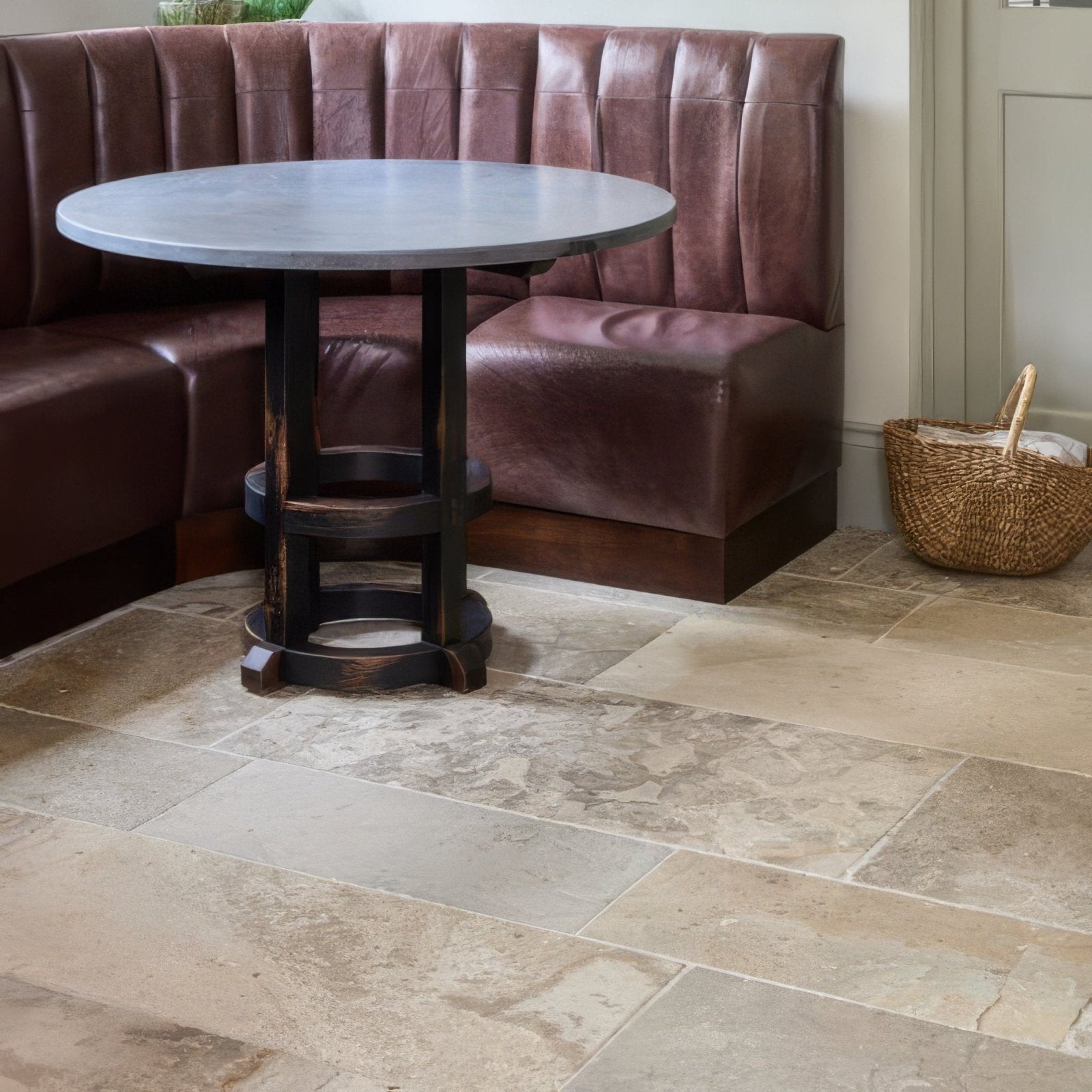 Round gray limestone table with dark wooden legs featuring a rustic industrial design in vieux bourgogne finish