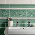 Vintage white sigma moulding featuring a decorative green ceramic tile with an embossed floral pattern above a sink