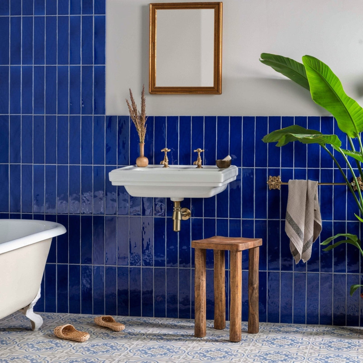 White ceramic wall-mounted sink with gold-toned faucets and plumbing in vogue light blue stone on chalk finish