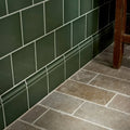 Dark green rectangular ceramic tiles with white grout and matching baseboard molding in victorian style wall skirting