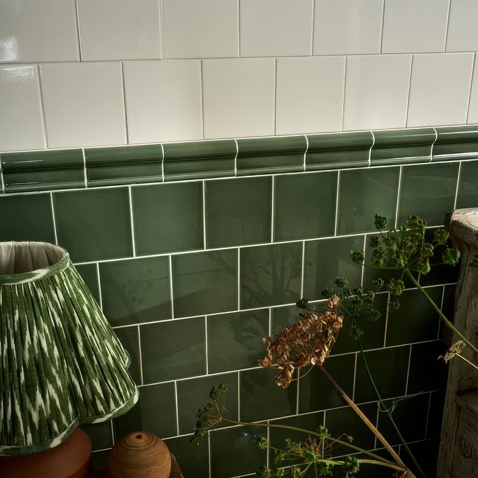 Dark green glossy ceramic subway tiles with white grout form a victorian style wall backsplash in cabbage green square