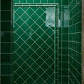 Deep emerald green glossy ceramic tiles with crackle glaze arranged in a diamond pattern with white grout lines