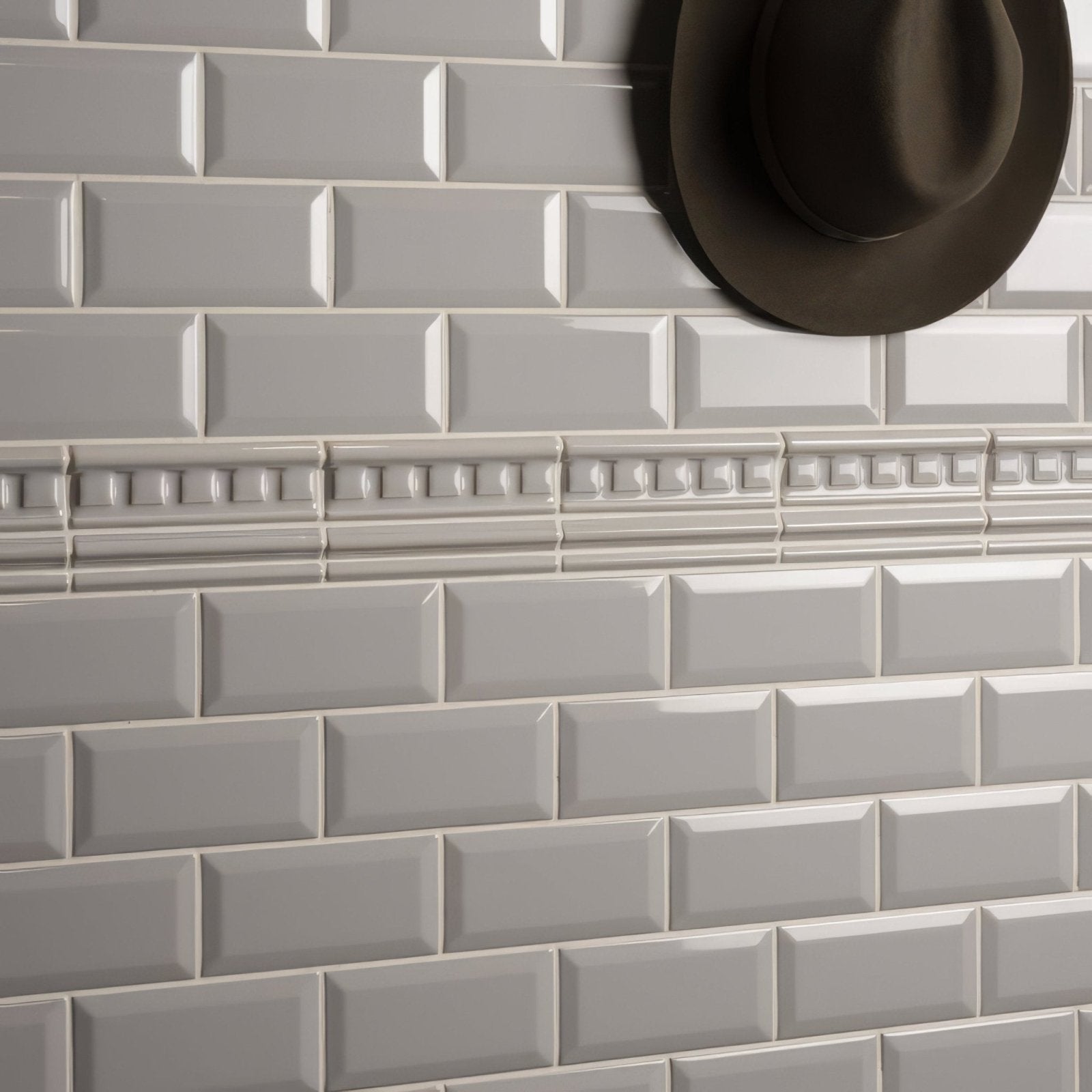A sleek matte-finished gray subway tile wall with decorative beaded dentil moulding border in westminster grey