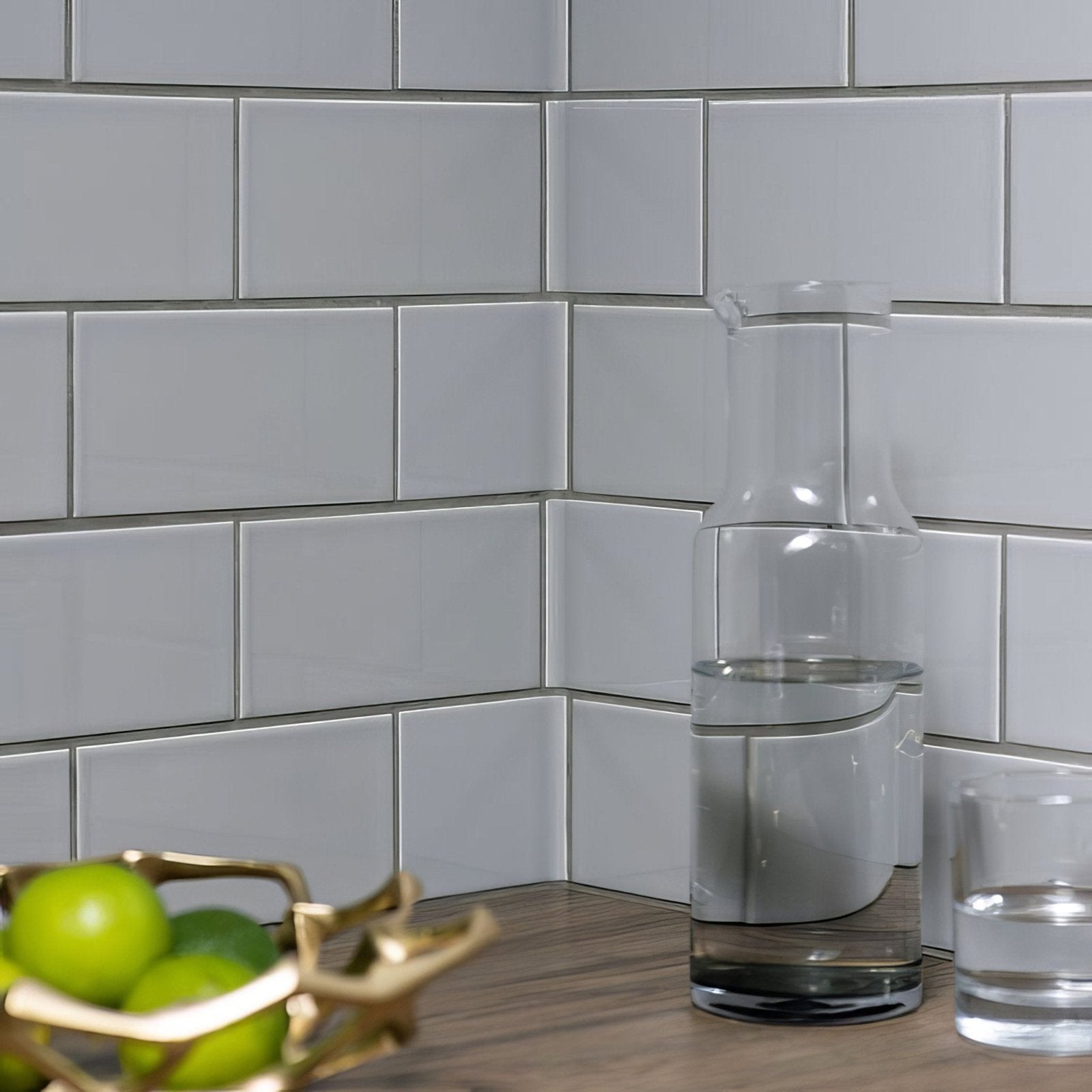 Clear glass carafe with narrow neck and wide base filled halfway with water in westminster grey half tile setting