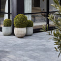 Three round green topiary bushes in textured gray wexford limestone cobble tumbled finish stone planters