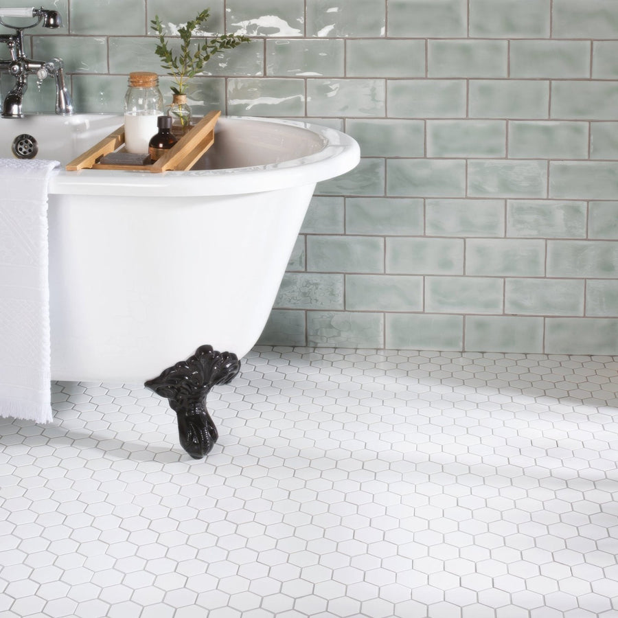 White large honeycomb floor mosaic under a white clawfoot bathtub with black ornate feet