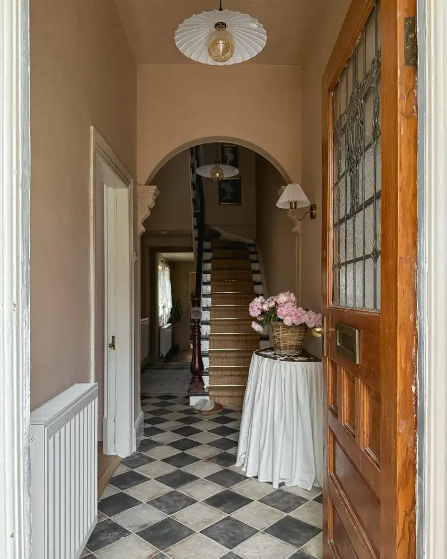 Period-inspired interior with patterned floor tiles and a round table.