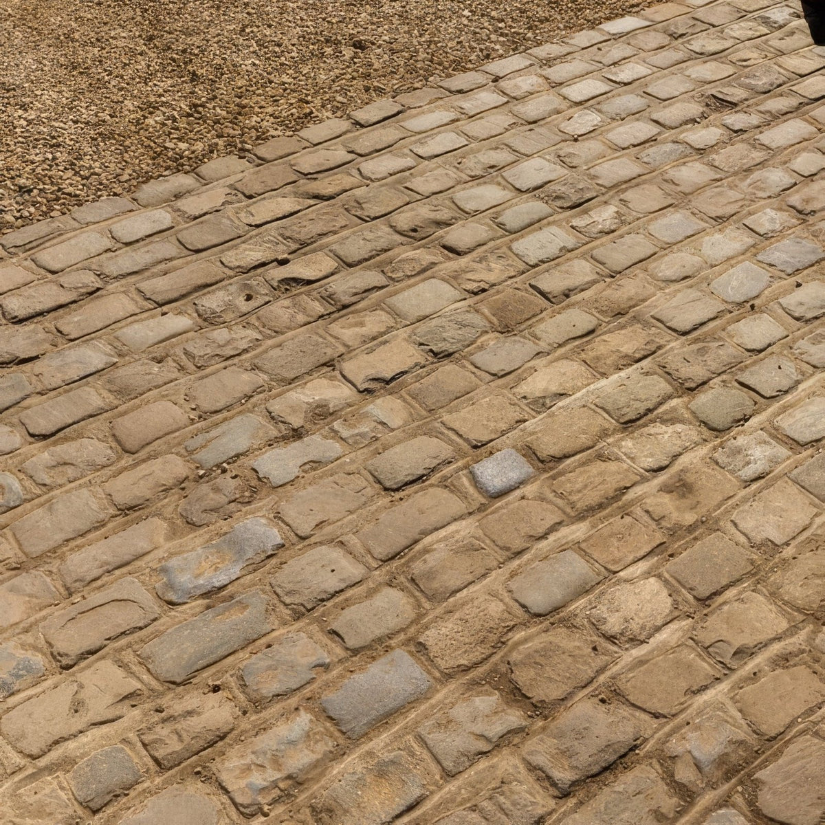 Weathered beige windsor sandstone cobble pavement with irregular reclaimed and sawn stones in a traditional pattern