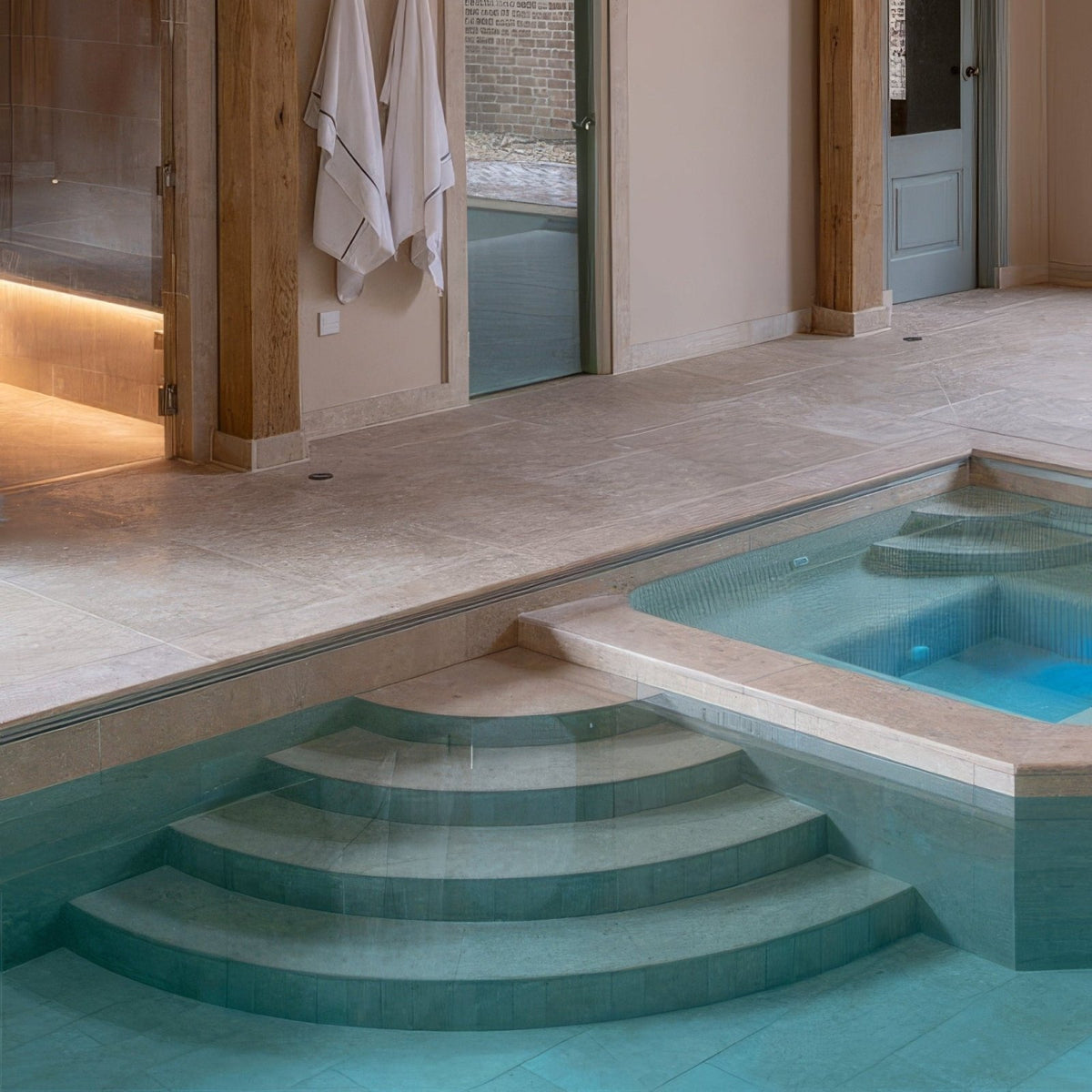 Modern indoor pool with curved tiled steps in wychwood limestone tumbled and etched finish