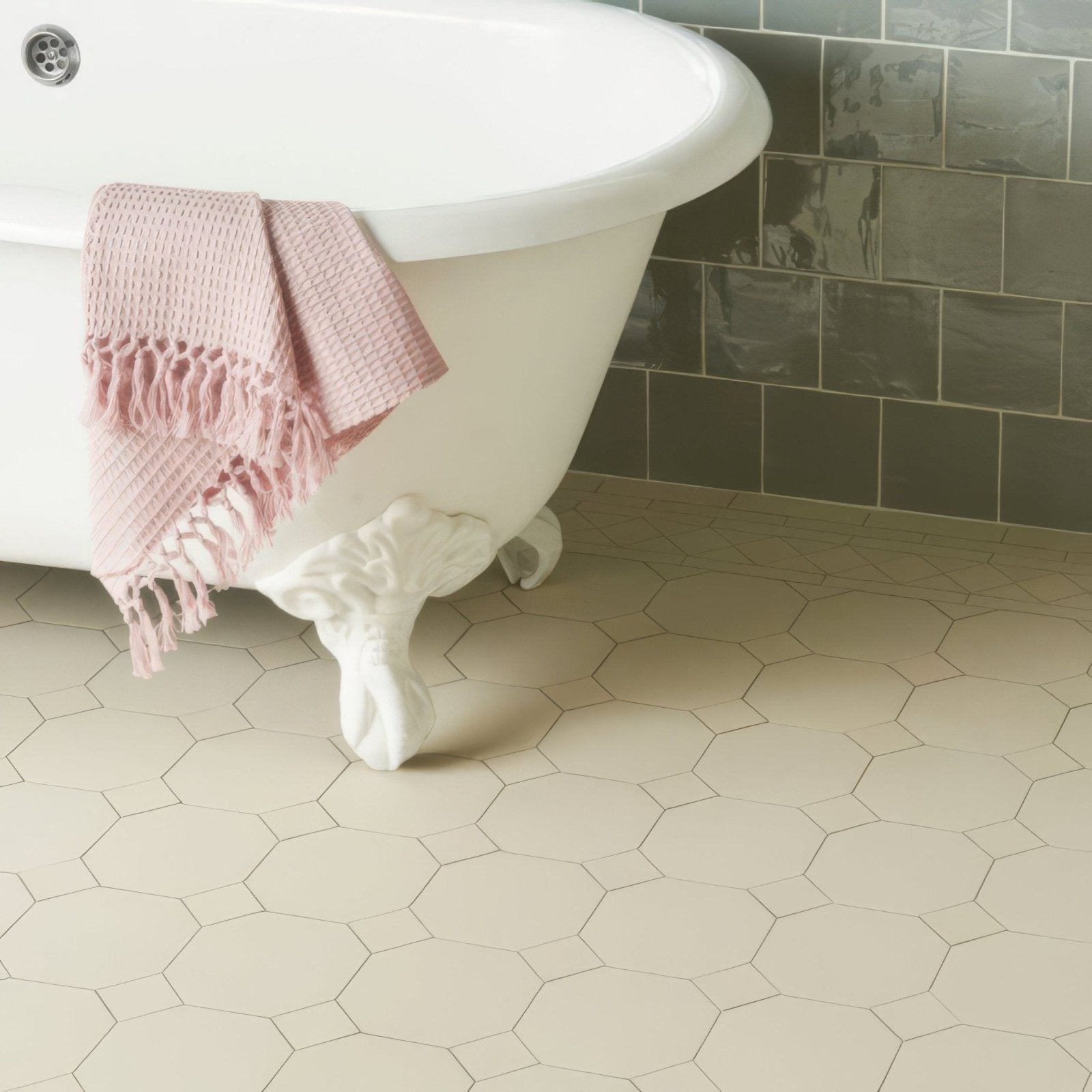 A soft pink waffle-weave towel with fringed edges draped over a white york dover clawfoot bathtub