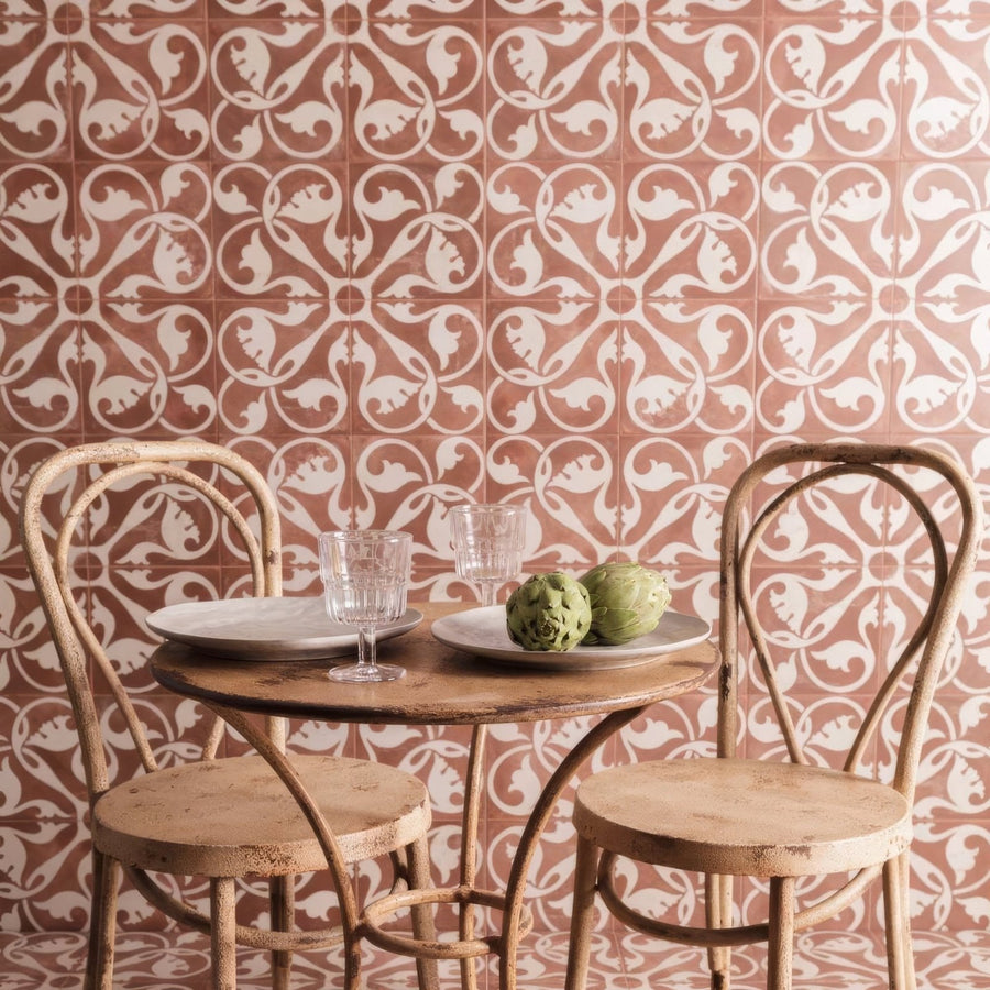 Rustic wooden table with round top and metal legs between two chairs against a patterned zayda mocha matt ceramic tile wall