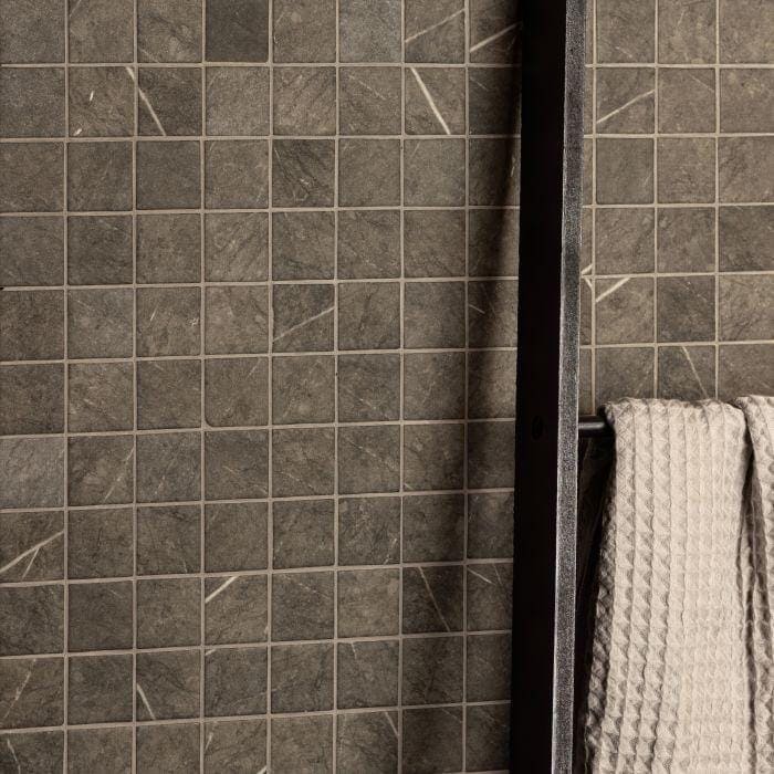 Burano Grey Recycled Glass Mosaic dark grey glass mosaic wall with a beige waffle towel on a black rack