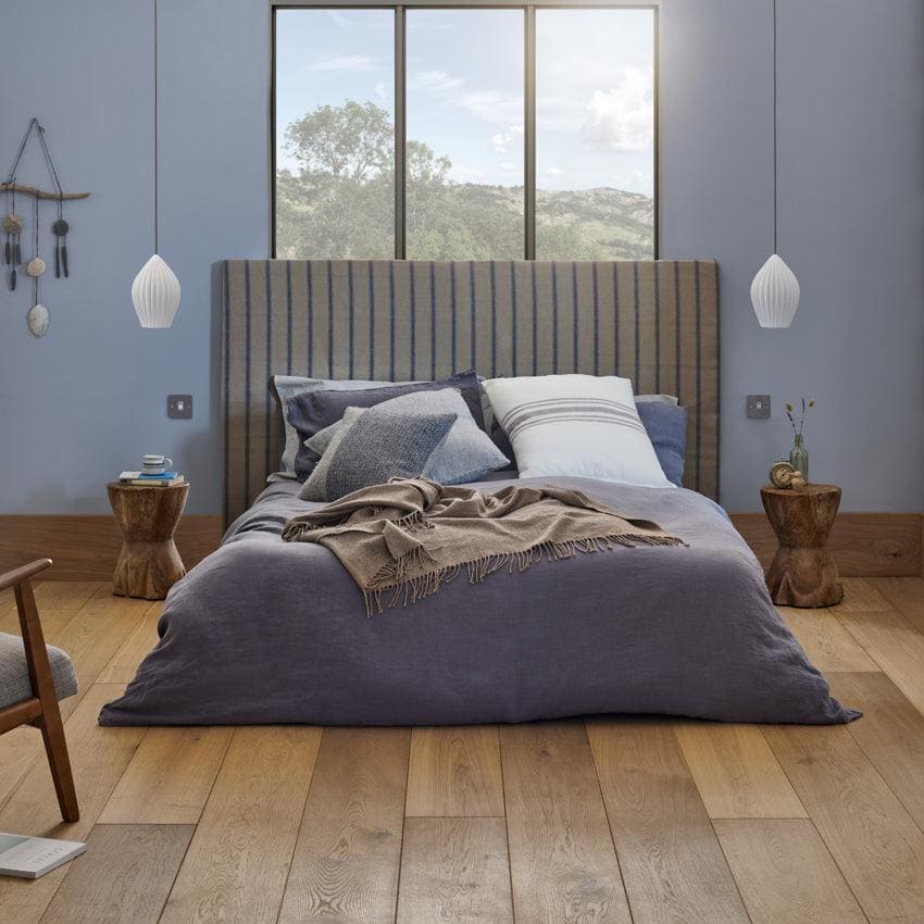 A modern Chepstow washed oak bed with a tall vertically striped gray upholstered fabric headboard