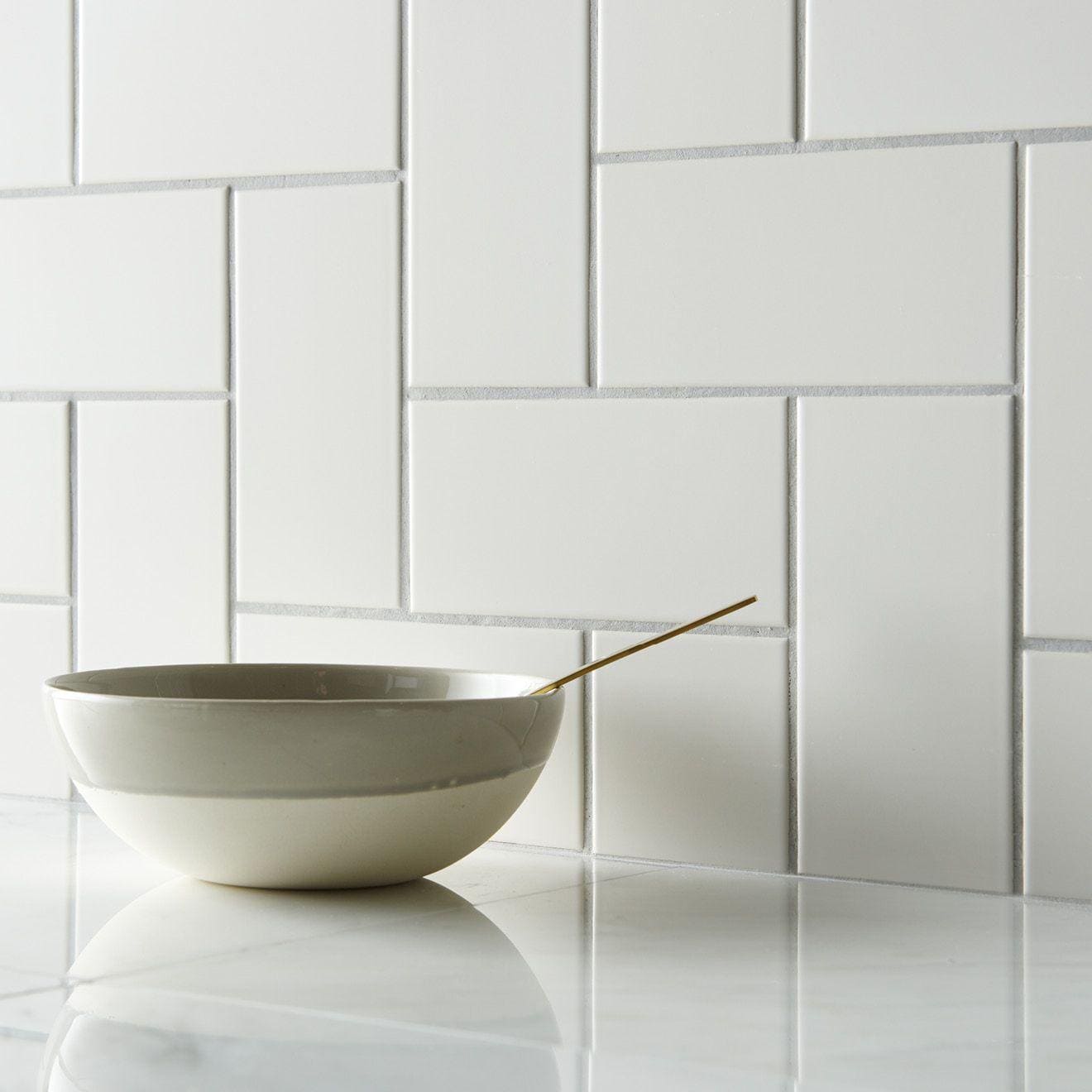 A minimalist off-white ceramic daisy satin half tile bowl with smooth matte finish and subtle horizontal banding