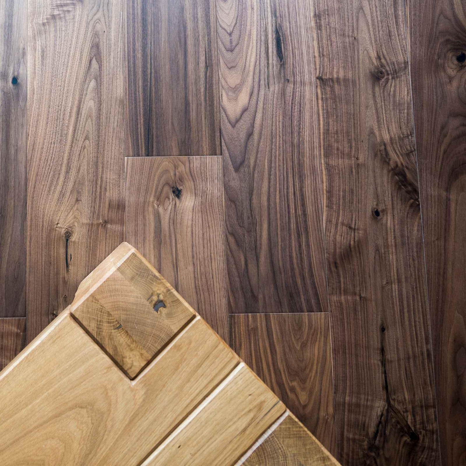 Dark walnut american black walnut hardwood floor with a contrasting light-colored wooden plank in the foreground
