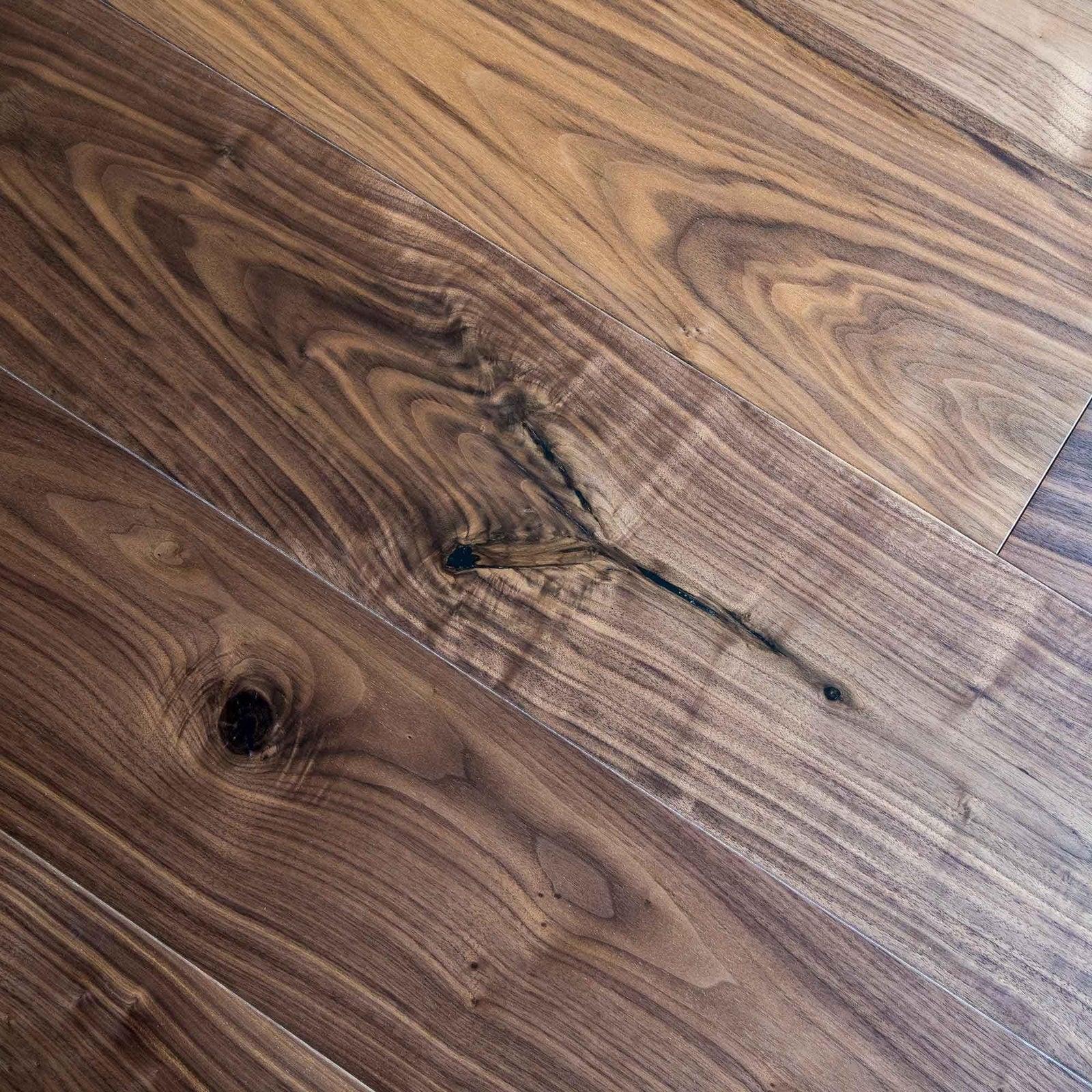 Rich dark brown american black walnut hardwood flooring with natural wood grain pattern and visible knots