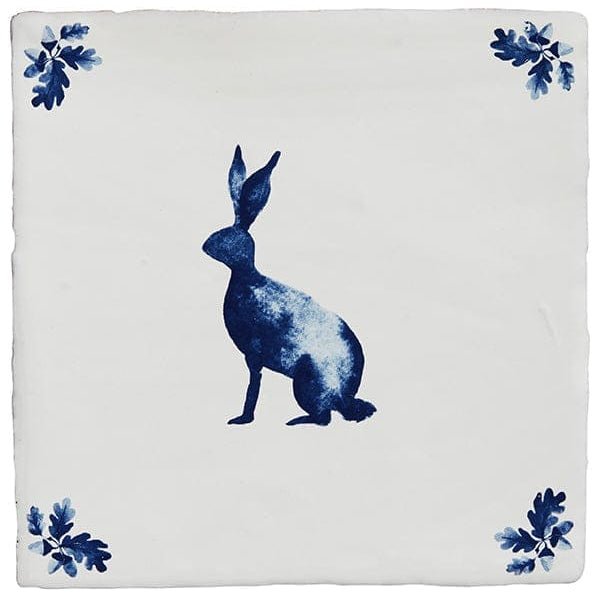 White ceramic tile from dyrham dairy ceramic decors featuring a blue rabbit silhouette with leafy corner accents