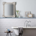 White ornate mirror with intricate floral detailing on fabrique rosaline french blue frame